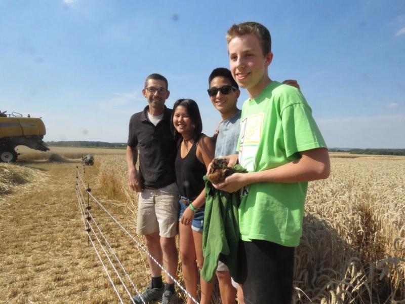 La famille Vandevelde devant la zone protégée par la clôture électrifiée pour protéger le nid des prédateurs. Dans les mains d’un des fils, un jeune busard cendré.