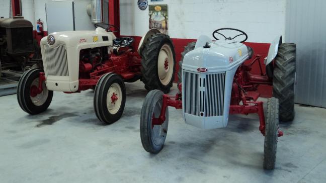 Le Ford 8N (à droite) côtoie directement son successeur, le Ford NAA  Golden Jubilee, sous le toit du hangar abritant une partie de la collection.